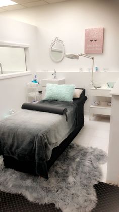 a bed sitting in the middle of a bedroom next to a sink and mirror on top of a tiled floor