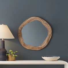 a table with a lamp and a mirror on it next to a wall mounted shelf