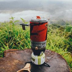 a camp stove sitting on top of a tree stump next to a pair of sunglasses