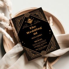 a black and gold wedding program on a plate with white napkins next to it