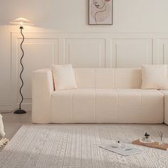 a white couch sitting on top of a rug in a living room next to a lamp