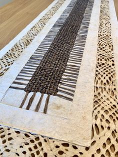 an intricately designed table runner on top of a wooden table with holes in it