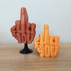 two hand shaped objects sitting on top of a wooden table next to an orange object