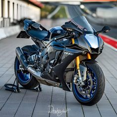 a black and blue motorcycle parked on top of a brick road