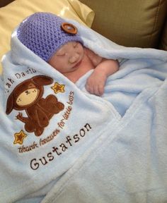 a baby wrapped in a blanket with a monkey on it