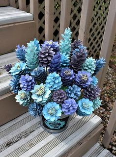 a vase filled with blue and purple flowers sitting on top of a wooden porch bench