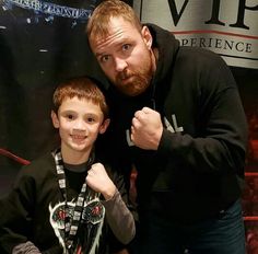 a man standing next to a young boy in front of a sign that says,