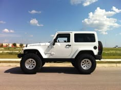 a white jeep is parked on the side of the road in front of some grass