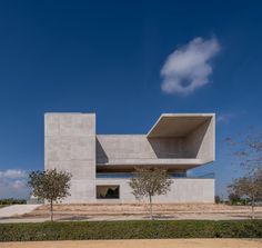 an architecturally designed concrete building with trees in the foreground