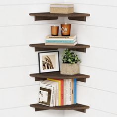 three wooden shelves with books and pictures on them in the corner of a white wall