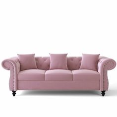 a pink couch with four pillows on it's back and two armrests