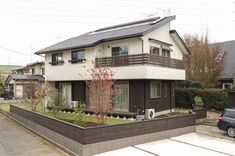 a car parked in front of a two story house with a green roof and balcony