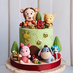 a cake with winnie the pooh figurines on top and decorations around it