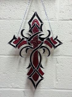 a red and black cross hanging on a white brick wall