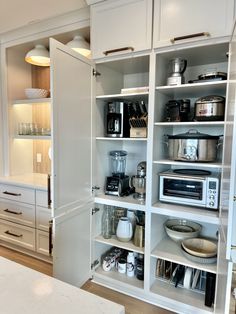 a kitchen with white cupboards filled with appliances