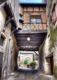 an alley way with stone buildings and brick walls on both sides, surrounded by cobblestones