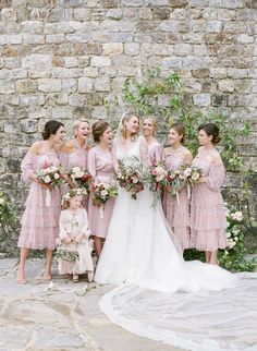 a group of bridesmaids standing in front of a brick wall