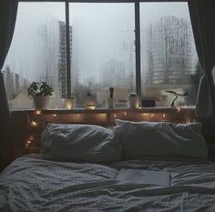 a bed sitting in front of a window covered in rain