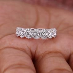 a close up of a person's hand holding a wedding ring with three stones