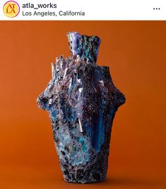 a blue vase sitting on top of an orange table next to a red wall with the words atlas works los angeles, california