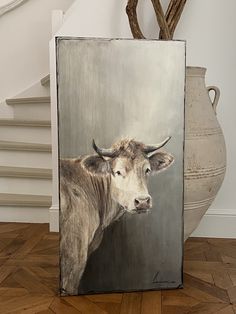 a painting of a cow with horns on it's head is displayed in front of a staircase