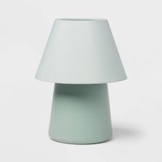 a white lamp sitting on top of a table next to a light green vase with a white lampshade