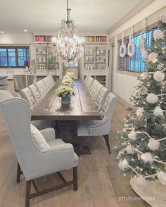 a dining room table surrounded by chairs and a christmas tree in the middle of the room