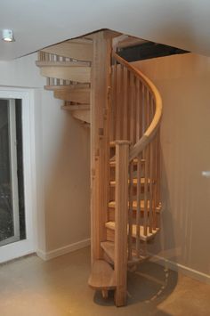 a wooden spiral staircase in an empty room