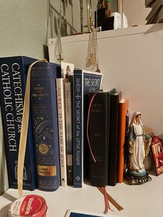 several books on a shelf next to a statue and other items in front of a window