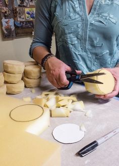 a woman cutting cheese with a pair of scissors