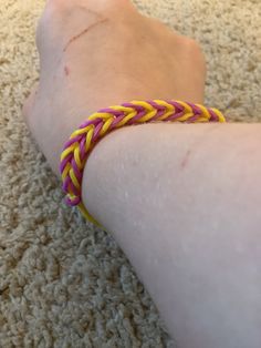 a person's foot with a yellow and pink braided bracelet on top of it