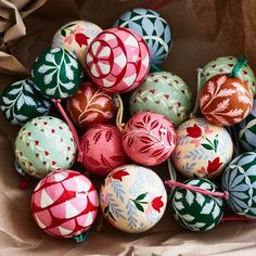 a pile of colorful painted eggs sitting on top of brown paper