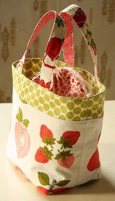 a small bag sitting on top of a table next to a white wall with strawberrys and polka dots