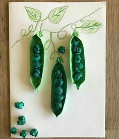 three peas are sitting on top of a piece of paper with green leaves and beads