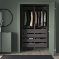 an open closet with clothes hanging on the doors and drawers in front of it, next to a black rug