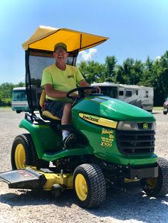 a man riding on the back of a green tractor