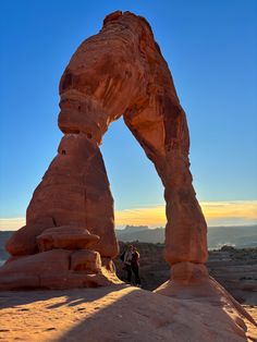 two people are standing under an arch in the desert