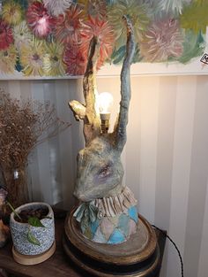 an animal head on top of a table next to a vase with flowers in it