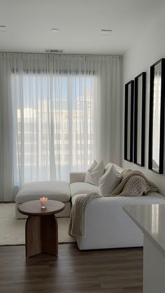 a living room filled with furniture and a large window covered in sheer curtains next to a coffee table