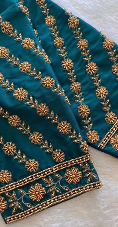 two pieces of blue and gold embroidered fabric on a white tablecloth with golden beading