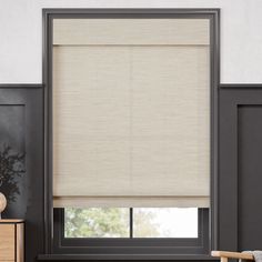 a living room with a large window covered in beige roman blind shades and a wooden chair