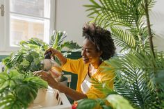 a woman is watering her plants in the house