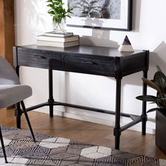 a black desk with two books on it and a chair in front of it next to a potted plant