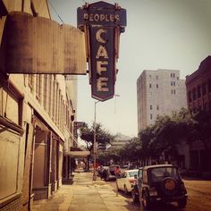 an old car is parked on the side of the road in front of a cafe