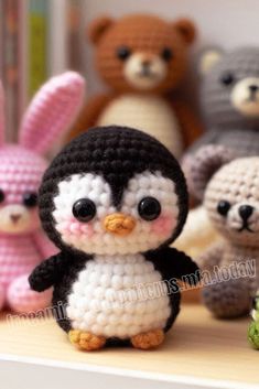 small crocheted penguins and teddy bears on a shelf with stuffed animals in the background