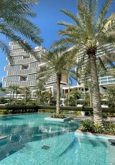 an outdoor swimming pool with palm trees and buildings in the backgroung area