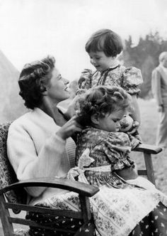 an old black and white photo of two women sitting on a chair with a child