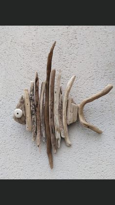 a sculpture made out of driftwood on the side of a building that has been painted white