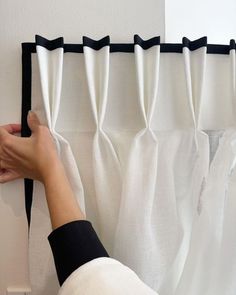 a person is pulling up the curtain with their hand and pressing down on the black trim