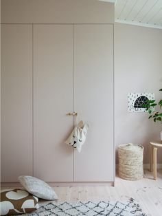 a room with pink walls and white furniture in the corner, along with a potted plant